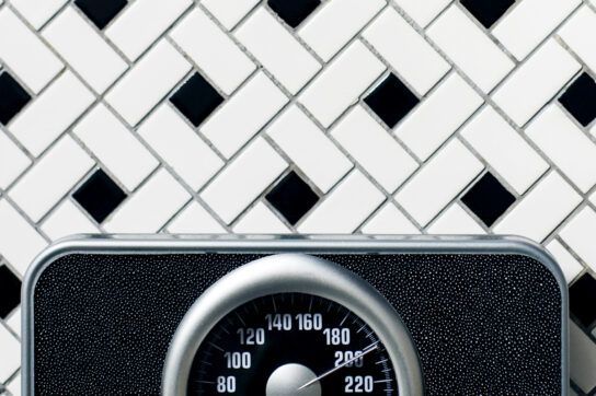 Analogue bathroom scales on a bathroom floor registering 200 pounds depicting insulin weight loss