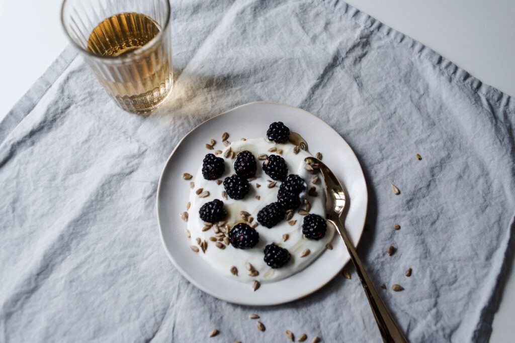 Bowl of yogurt with blackberries and seeds.