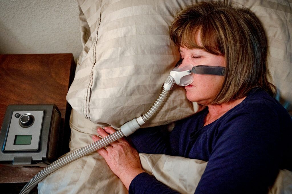 Woman in bed with CPAPmachine for sleep apnea