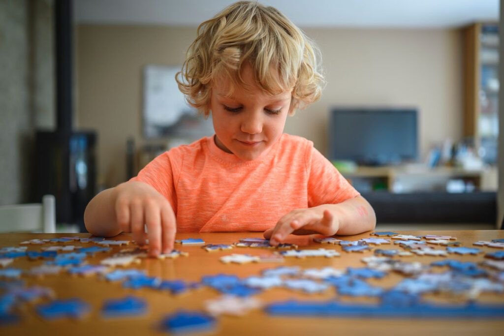 A young child playing with a jigsaw puzzle, showing their brain development being supported by omega-3 for kids.