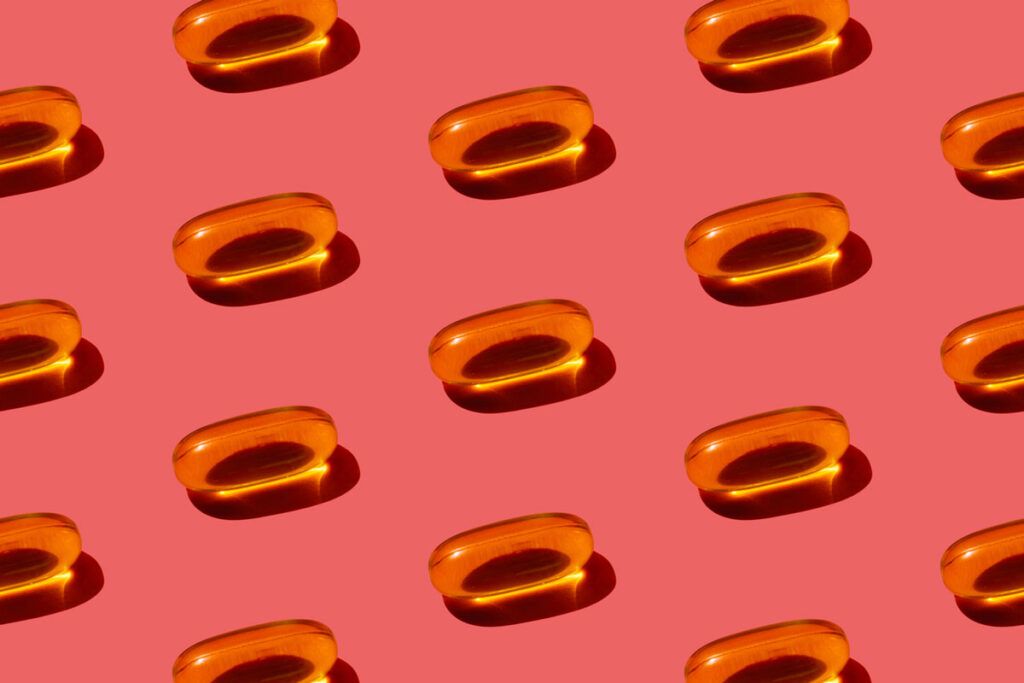 A pattern of omega-3 capsules recommended for adults against a pink background