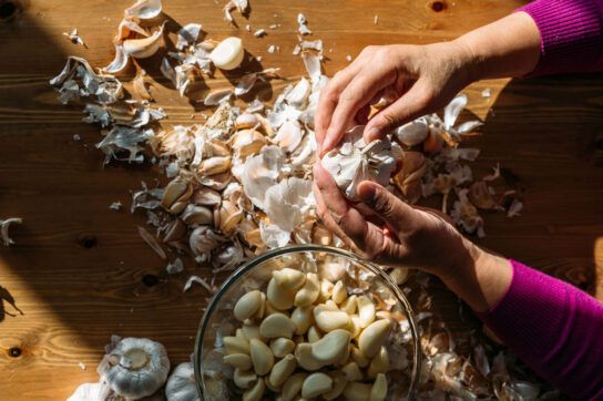 A person peeling cloves of garlic, which is a natural beta blocker option.