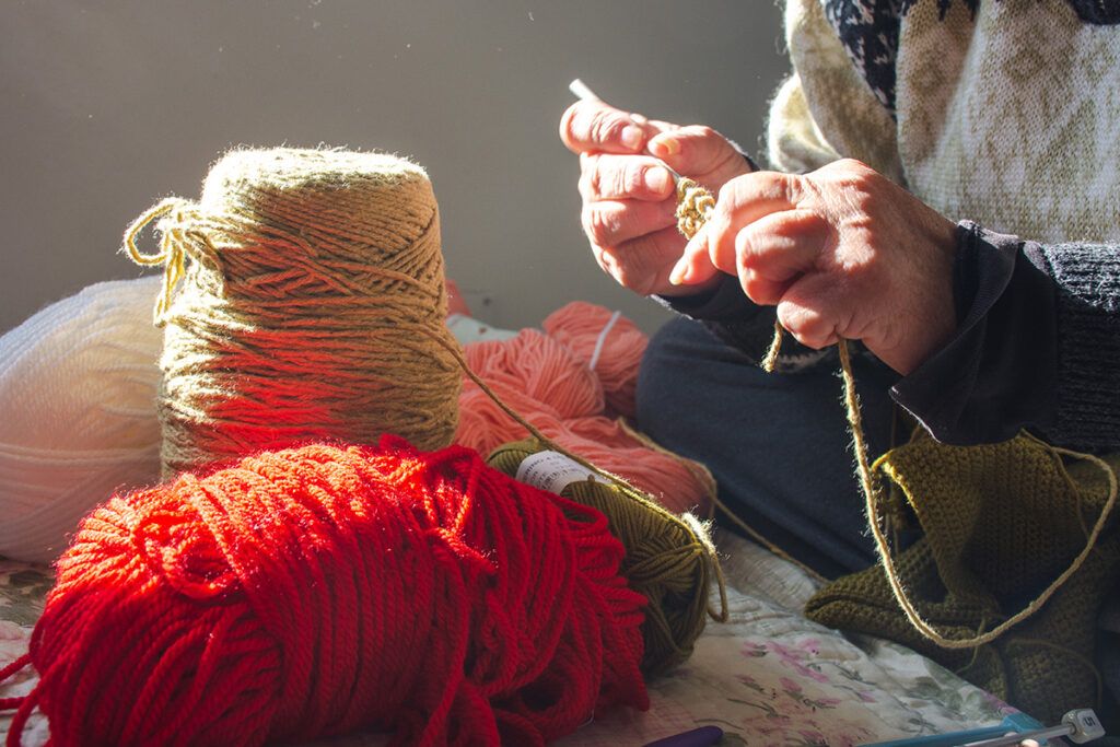 Close-up of senior woman's hands knitting, with hands displaying Hebeden's nodes from arthritis