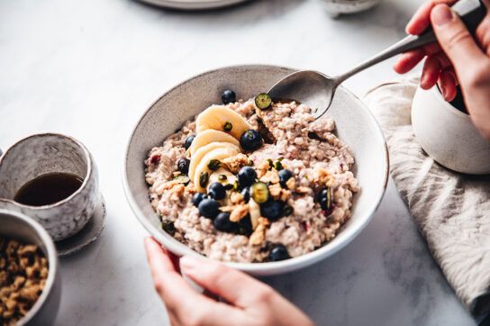 A bowl of oatmeal with banana and blueberries in it, which can be good for gout.