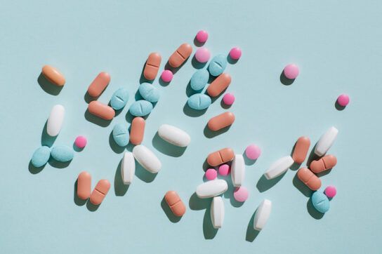 Colorful pills and capsules on blue background. Minimal medical concept. Flat lay, top view.