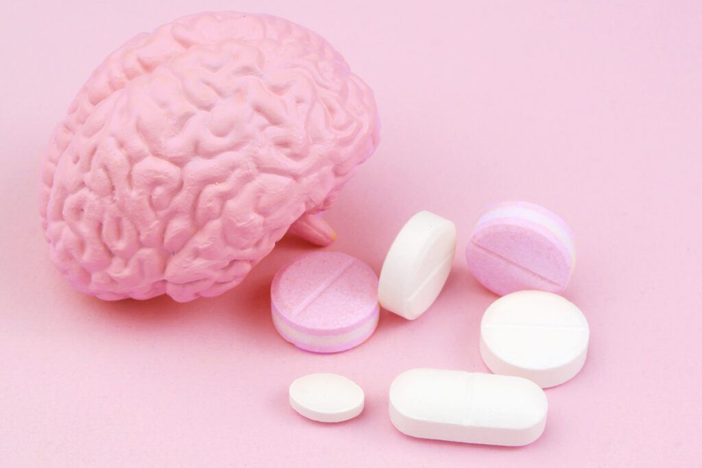 Drug tablets and pills next to a brain model symbolizing medications that cause serotonin syndrome