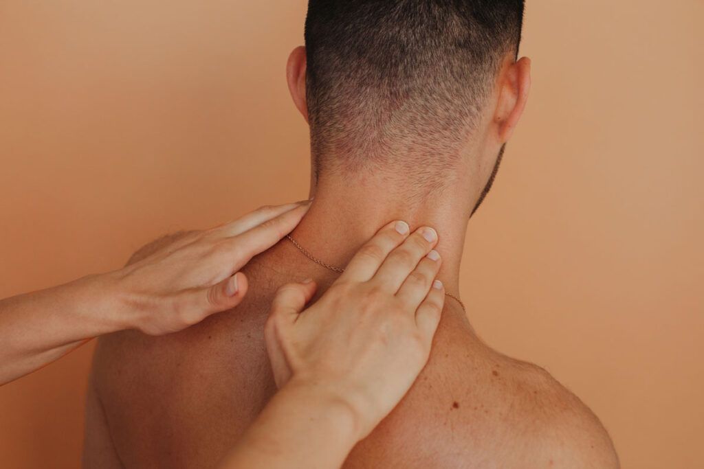 Image of 2 hands reaching out to massage someone's neck and shoulders.