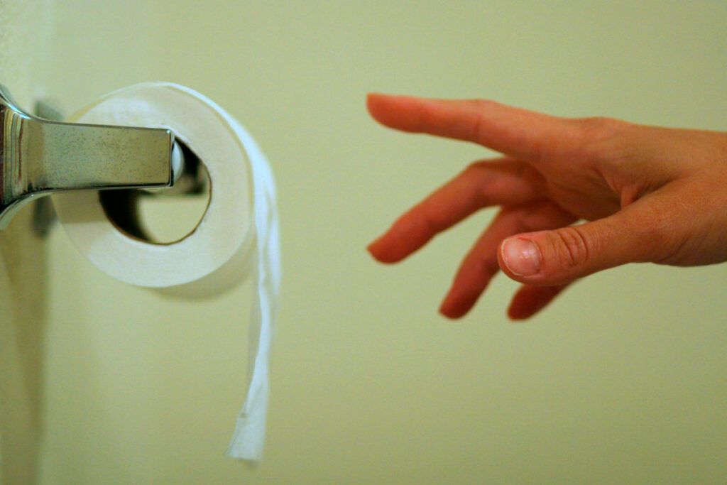 Close up shot of a person's hand reaching for the toilet roll depicting what are some natural remedies for overactive bladder