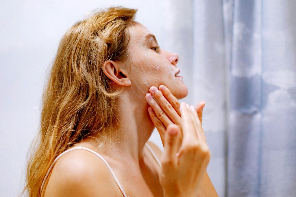 Image of female applying face wash to depict rosacea treatment.