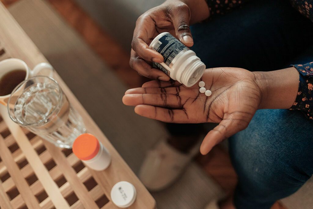 Someone pouring aspirin into their hand from a bottle, wondering whether aspirin can lower blood pressure.