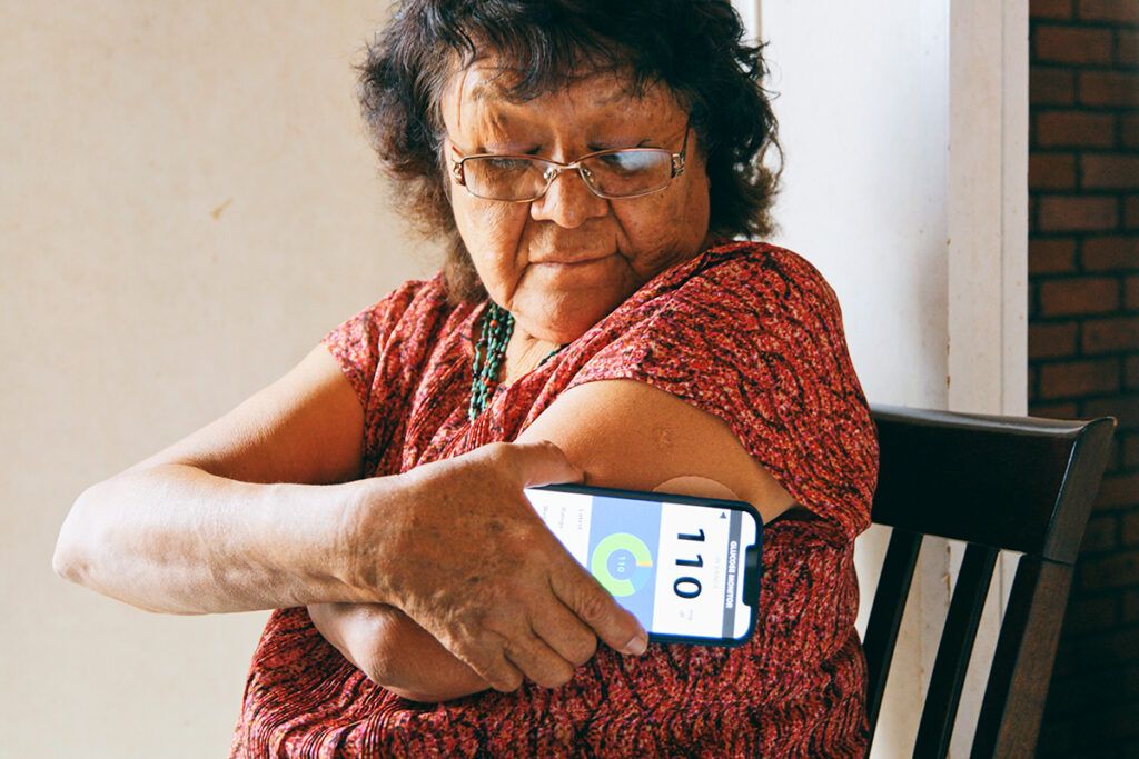 An older adult checking their glucose levels with a smartphone to avoid having uncontrolled diabetes.