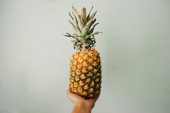 Hand holding a pineapple for acid reflux test