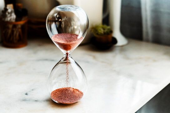 An hourglass sand timer sitting on a table representing the time it takes and signs metformin is working.