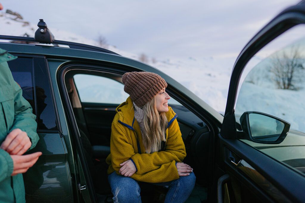 Female sitting in her car overlooking snowy hills, to depict post-holiday bluess