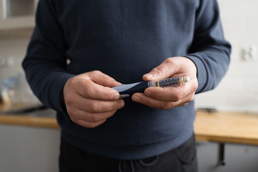 Adult male holding an epi pen after researching an epipen for allergies