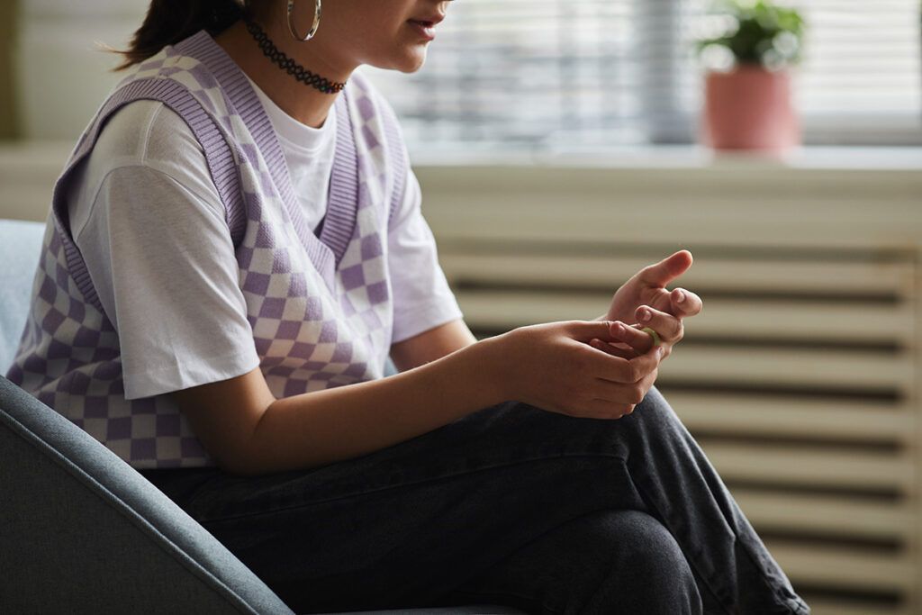 Female sat down and fidgeting with a ring on her finger to depict treatment for binge eating disorder.