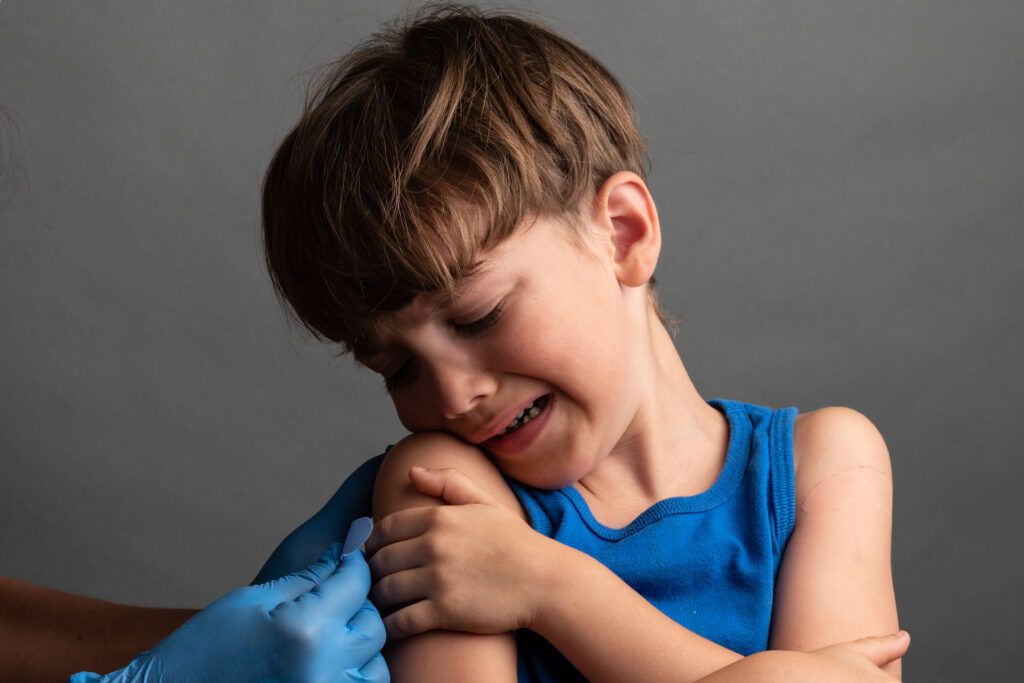 Child holding their upper arm in pain to depict tips on how to make shot not hurt.