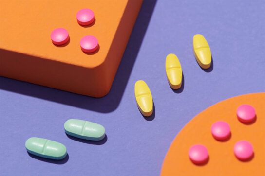Several brightly coloured pills on a surface purple surface to depict statin medication options.