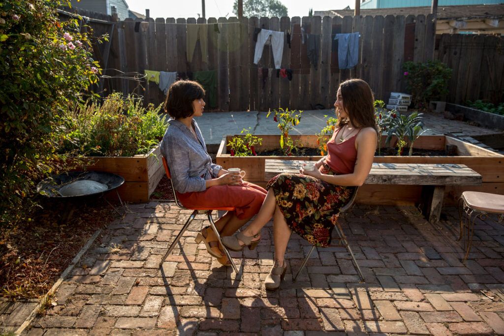 Two people sat in a garden having a chat, to depict a coping strategy for panic attacks.