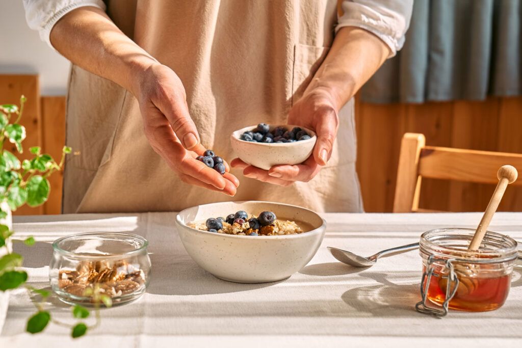 Woman serving oatmeal and blueberries as a daily fiber intake