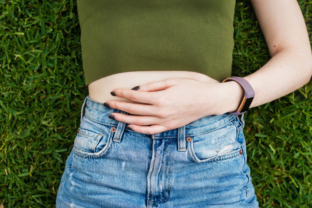 Person laying on grass with a hand on their stomach to portray natural treatment options for PMDD.