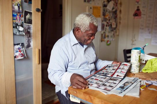 An older adult smiling reading a magazine. He may be experiencing long COVID disability.