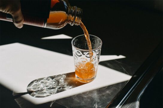 Bottle of apple cider vinegar being poured into a glass as we wonder, does apple cider vinegar lower blood pressure