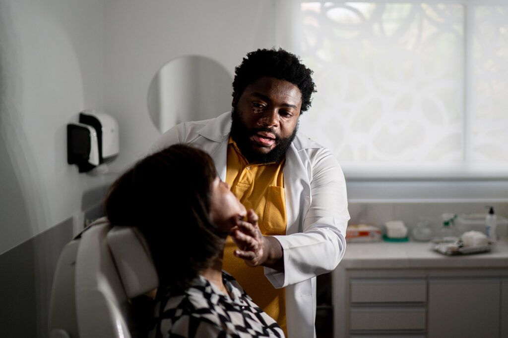 Healthcare professionals examine a person’s face to depict questions to ask a doctor about psoriasis.