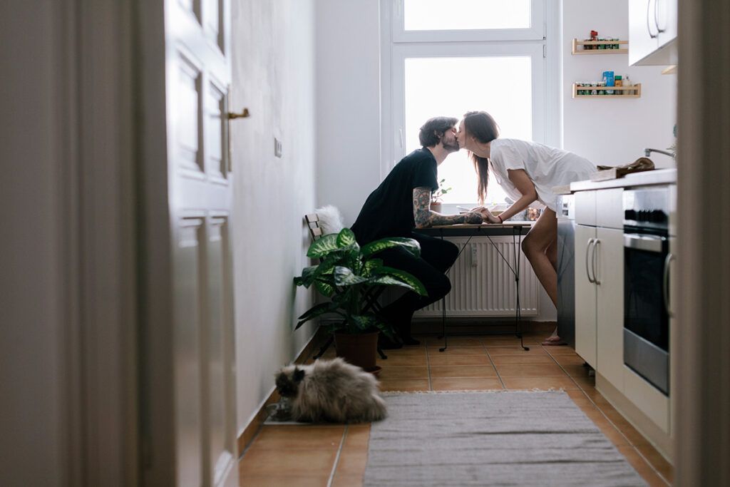 A couple kissing over a table in a kitchen, wondering what medications can cause erectile dysfunction.