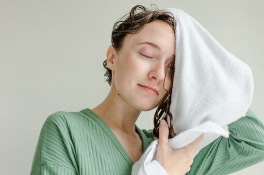 Adult female using a towel to dry her hair after looking at information on how to use clobetasol proprionate on the scalp