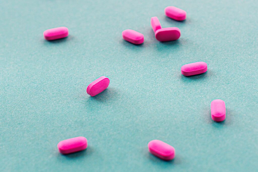 Pink pills scattered across a blue background to show medications that you should not take with Benadryl.