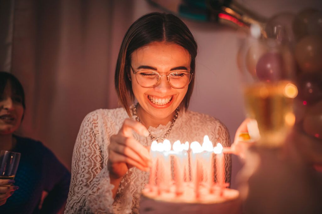 Female smiling looking at her birthday cake that has lit candles and enjoying her birthday after possibly taking phenobarbital for seizures