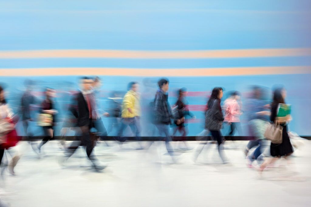 A group of people walking by in a blur, representing the blurry vision caused by migraine.