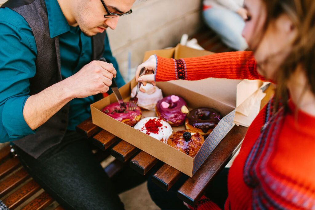 Couple eating sugary donuts, which may elevate their cholesterol levels