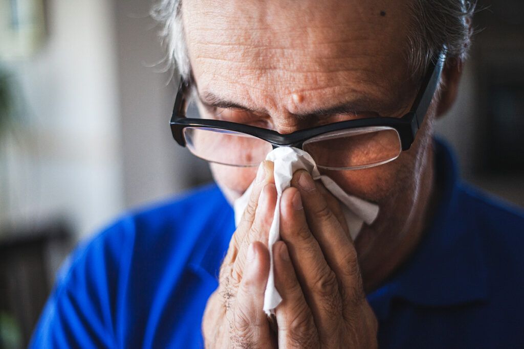 Person blowing their nose to depict the safest antihistamines for older adults.