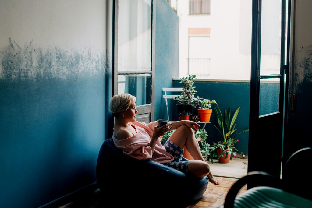 Female sitting on a beanbag with a mug chilling out.