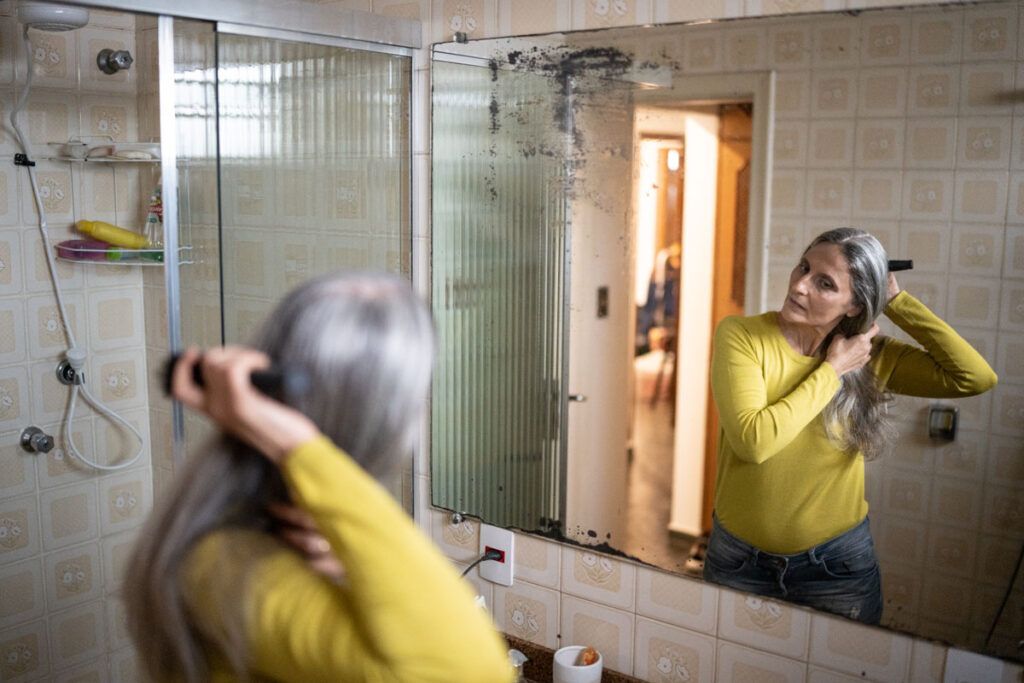 Older woman brushing hair after applying Rogaine for women hair loss