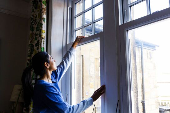 Woman with asthma closing window to avoid humidity related allergens and triggers