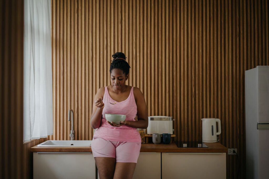 An adult leaning against a counter eating breakfast, after taking diltiazem on an empty stomach.