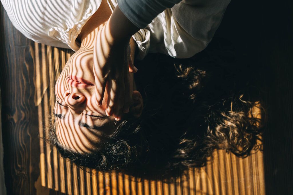 A person lying in a patch of sunlight to depict the difference between sunburn and sun poisoning.