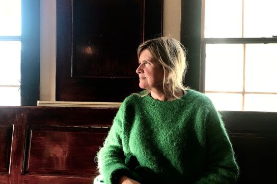 Woman around age 40 in green sweater looking to side