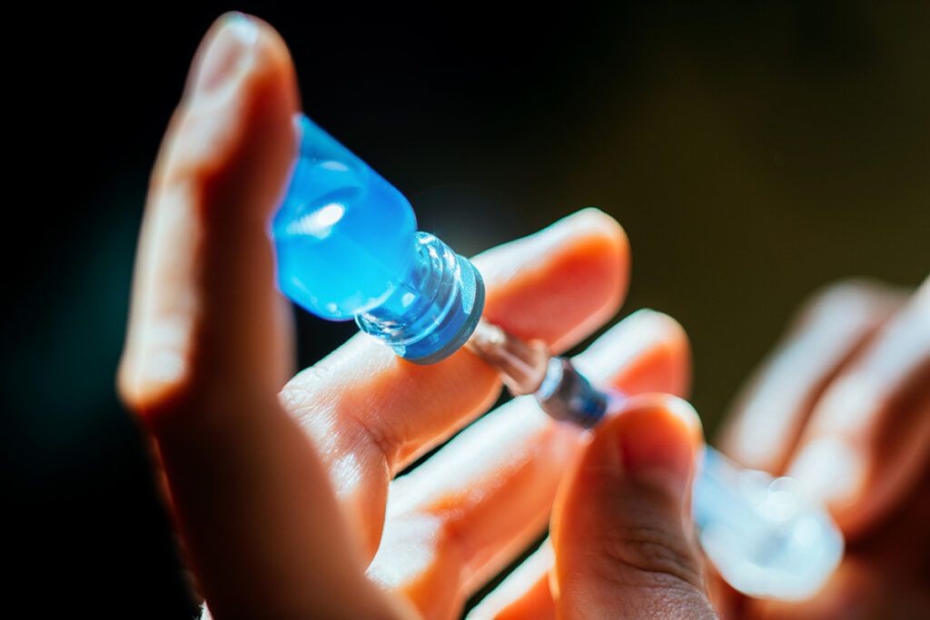 A person taking DMARD medication into a syringe.