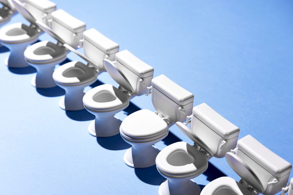 A row of toilets on a blue background. Most lids are open but one is closed. This represents types of poop.