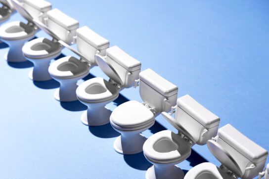 A row of toilets on a blue background. Most lids are open but one is closed. This represents types of poop.