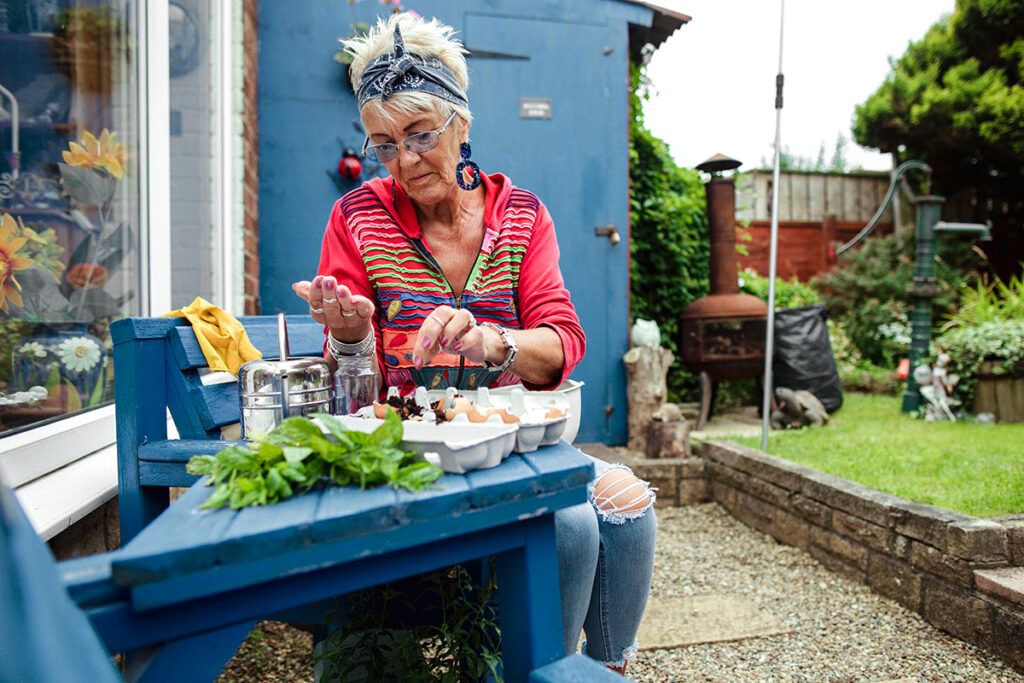 An older adult planting seeds in a garden, considering the signs of a stroke before it happens.
