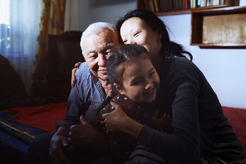 Three family members of different generations in an embrace, learning what to say to someone who is dying.