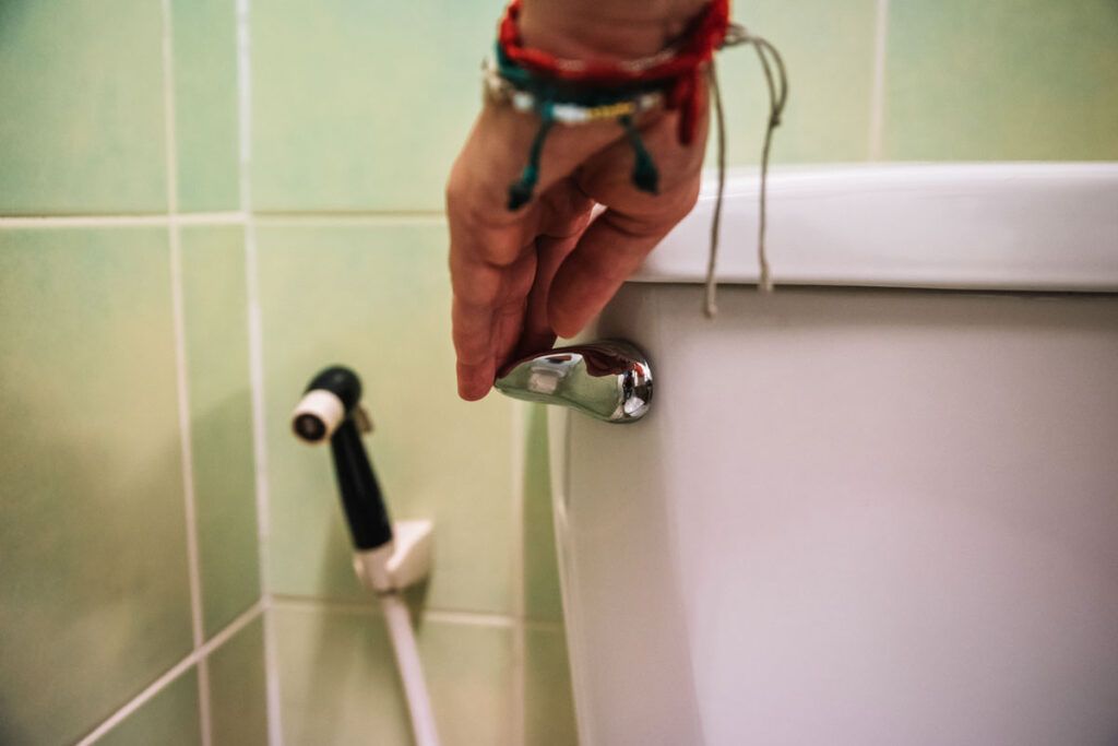 A hand flushing a toilet, representing drugs that make you pee a lot.