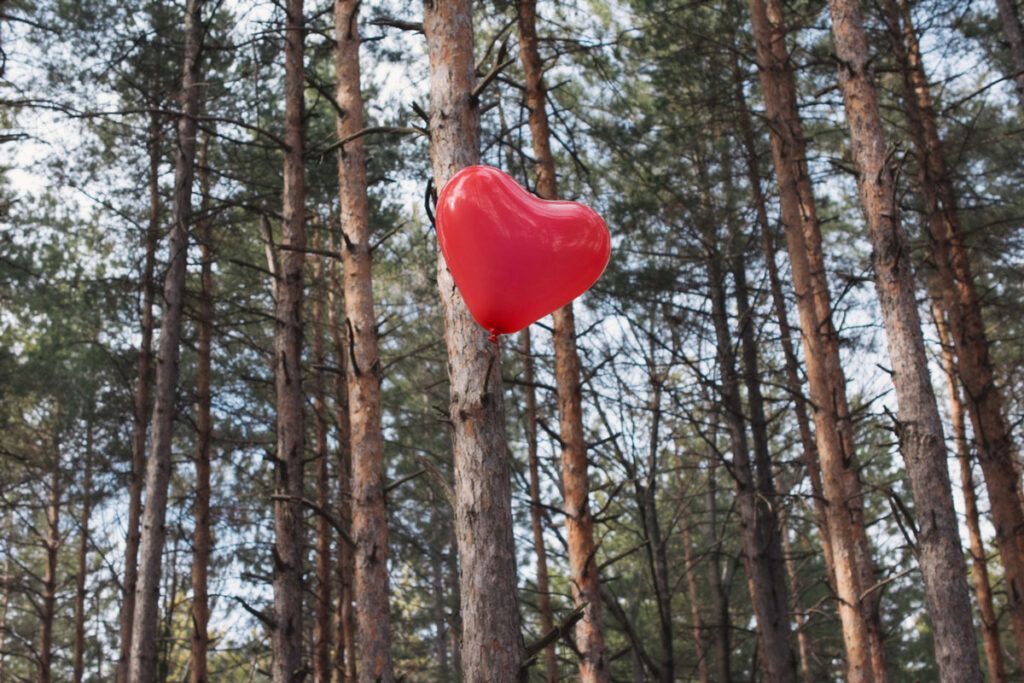A red heart-shaped balloon floating away in a forest, representing chest pain and anxiety.