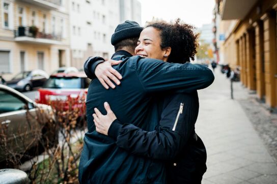 Two friends hugging in the street, after discussing how long depression lasts.