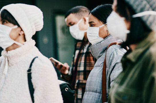 A group of people outside wearing medical masks, representing remdesivir and Paxlovid treatment for COVID-19.